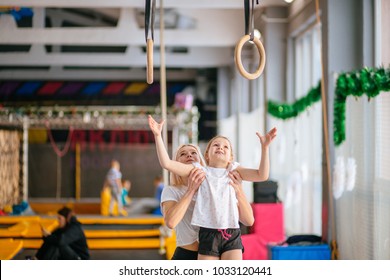 Mother helping her daughter to play sports on gymnastic rings - Powered by Shutterstock