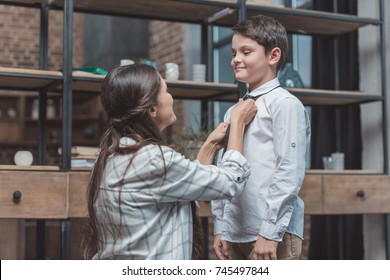Mother Helping Her Little Son Get Dressed And Tie A Necktie