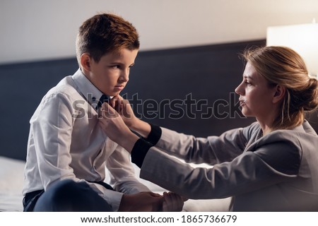 A Mother helping her son to get ready for school, buttoning up his shirt, telling him to behave and be a good boy at school.