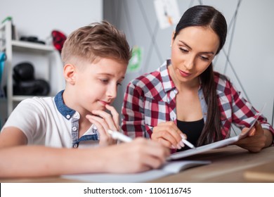 Mother helping her son with homework in teenage room at home
