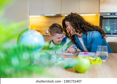 Mother helping and homework to her son indoor  Young mother doing homework and her son pointing to something written in his notebook as he stares thoughtfully at the page