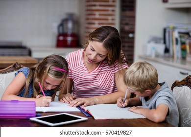 Mother helping kids with their homework at home