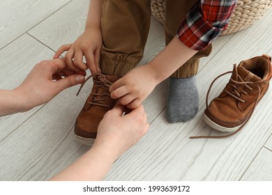 Mother helping son to tie shoe laces at home, closeup - Powered by Shutterstock