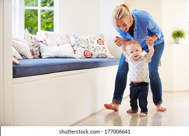 Mother Helping Young Son As He Learns To Walk