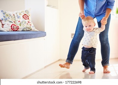 Mother Helping Young Son As He Learns To Walk