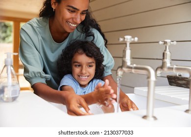 Mother helping young son wash hands in sink - Powered by Shutterstock