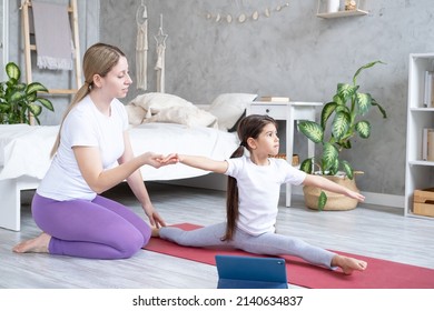 mother helps her daughter doing stretching exercising online with tablet at home - Powered by Shutterstock