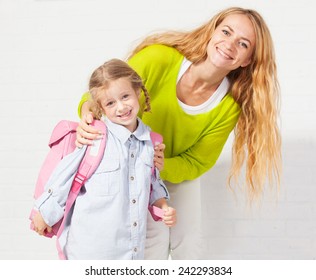 Mother Helps Her Daughter Get Ready For School. Mom Support Child To Wear A Backpack