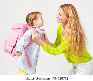 Mother Helps Her Daughter Get Ready For School. Mom Support Child To Wear A Backpack