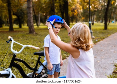 Mother Helps Her Son To Puts Protective Helmet For Riding Bike