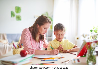 mother helps son to do lessons. home schooling, home lessons. the tutor is engaged with the child, teaches to write and count. out-of-school lessons with a teacher. happy baby in bright room with mom