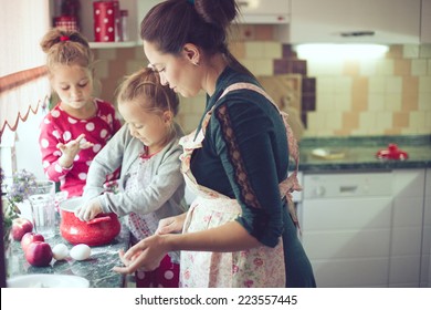 Mother With Her 5 Years Old Kids Cooking Holiday Pie In The Kitchen, Casual Lifestyle Photo Series In Real Life Interior