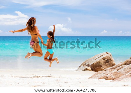 Mother with her 8 years old daughter resting on a tropical beach during summer vacations
