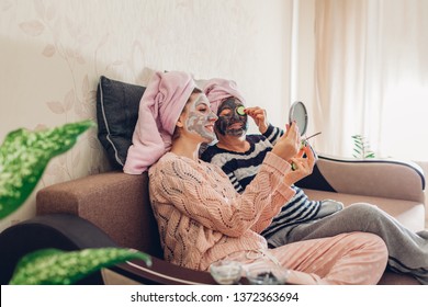 Mother and her adult daughter applying facial masks and cucumbers on eyes. Women chilling and having fun at home - Powered by Shutterstock