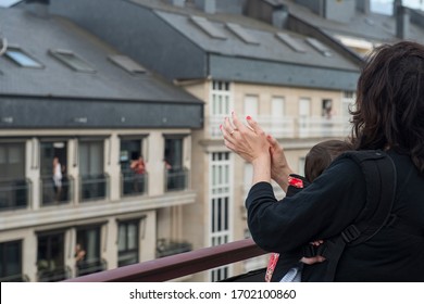 a mother and her baby applauding from the balcony in solidarity with the health personnel who are healing the covid-19 - Shutterstock ID 1702100860