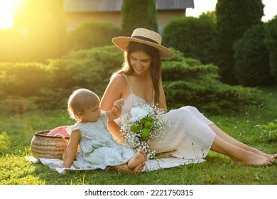 Mother with her baby daughter having picnic in garden on sunny day