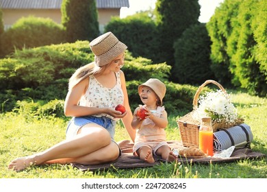 Mother with her baby daughter having picnic in garden on sunny day - Powered by Shutterstock