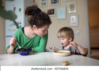 Mother With Her Baby Eating Soup In The Bright Kitchen At Home,  Real Interior, Mom With Dreadlocks, Casual