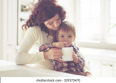 Mother with her baby having breakfast in the bright kitchen at home. Photo toned, still life. - Powered by Shutterstock