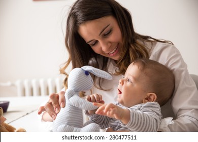 Mother And Her Baby Playing With Bunny Toy.