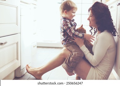 Mother with her baby playing with pet on the floor at the kitchen at home - Powered by Shutterstock