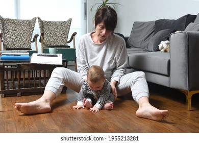 mother with her baby sitting on the wooden floor of the at home - Shutterstock ID 1955213281