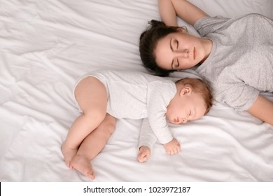Mother With Her Baby Sleeping On Bed At Home