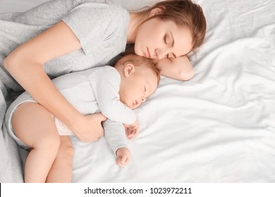 Mother With Her Baby Sleeping On Bed At Home