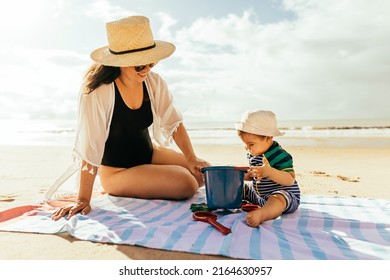 Mother and her baby son playing on the beach during summer vacation - Powered by Shutterstock