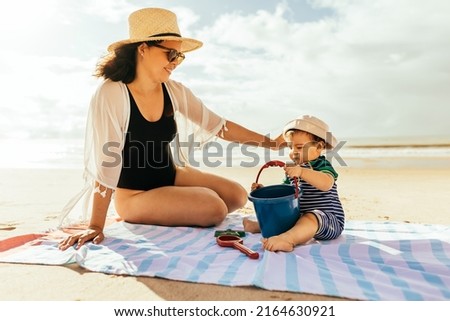 Mother and her baby son playing on the beach during summer vacation