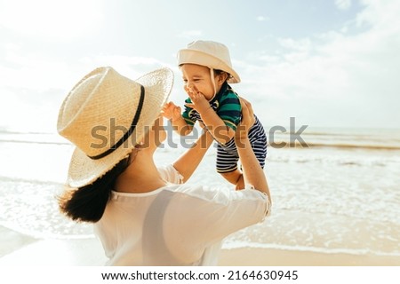 Mother and her baby son playing on the beach during summer vacation
