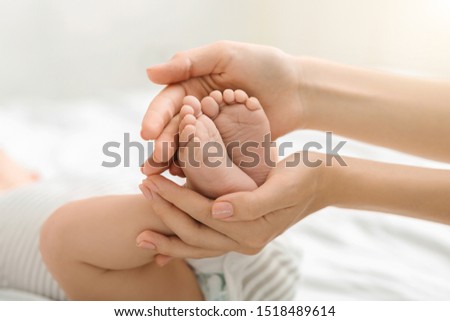 Mother and her child. Closeup of tiny baby feet in mom's hands.