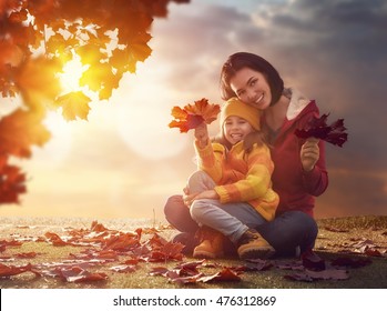 Mother And Her Child Girl Playing Together On Autumn Walk In Nature Outdoors. Happy Loving Family Having Fun.