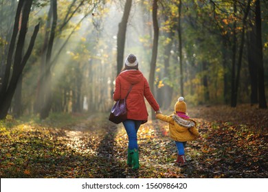 Mother and her child on a wallk at autumn forest. Back view