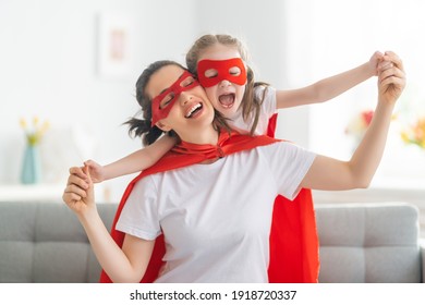 Mother and her child playing together. Girl and mom in Superhero costume. Mum and kid having fun. Family holiday and togetherness. - Powered by Shutterstock