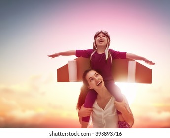 Mother and her child playing together. Little child girl plays astronaut. Child in an astronaut costume plays and dreams of becoming a spaceman. Happy loving family having fun.