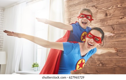 Mother And Her Child Playing Together. Girl And Mom In Superhero Costume. Mum And Kid Having Fun, Smiling And Hugging. Family Holiday And Togetherness.