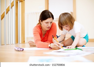  Mother And Her Child Sketching On Paper At Parquet Floor. Focus On Woman Only