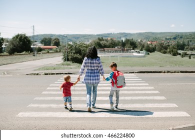 Mother And Her Children Crossing Road On Way To School