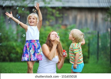 mother and her children play with bubble blower on green lawn - Shutterstock ID 151655018