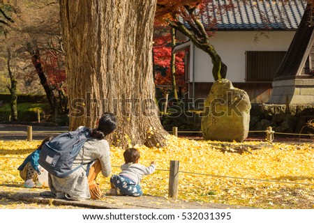 Mother and her children play with yellow leaves