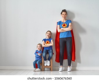 Mother And Her Children Playing Together. Girls And Mom In Superhero Costumes. Mum And Kids Having Fun And Smiling. Family Holiday And Togetherness.