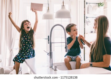 Mother With Her Children Playing With Water In Kitchen Sink At Home. Happy Lifestyle Family Moments.