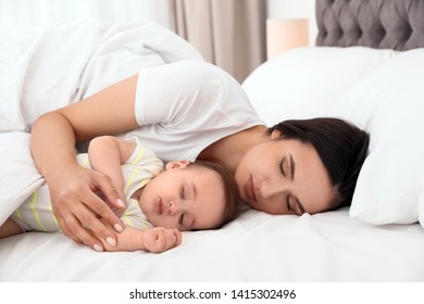 Mother And Her Cute Baby Sleeping On Bed Indoors