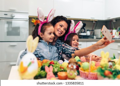 A Mother And Her Cute Daughters Are Taking Selfie Photo While Painting Eggs. Happy Family Are Preparing For Easter.