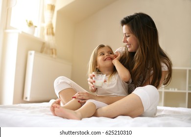 Mẹ với con gái nhỏ dễ thương của mình ngồi trên giường. Thưởng thức cùng nhau trong thời gian rảnh rỗi.