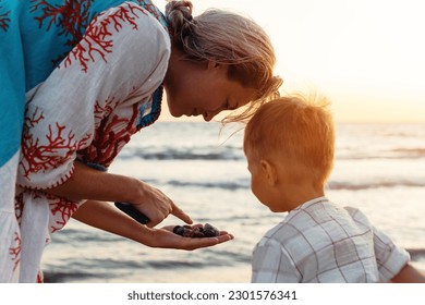 Mother and her cute little son collecting pebbles on shingle beach. - Powered by Shutterstock