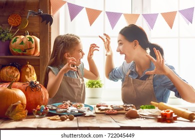 Mother And Her Daughter Having Fun At Home. Happy Family Preparing For Halloween. Mum And Child Cooking Festive Fare In The Kitchen.