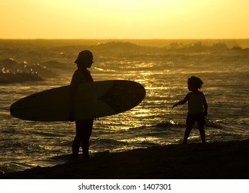 A Mother And Her Daughter On The Beach After Mom Has Spent The Afternoon Surfing In The Barbados Waves.