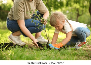 Mother and her daughter planting tree together in garden - Powered by Shutterstock